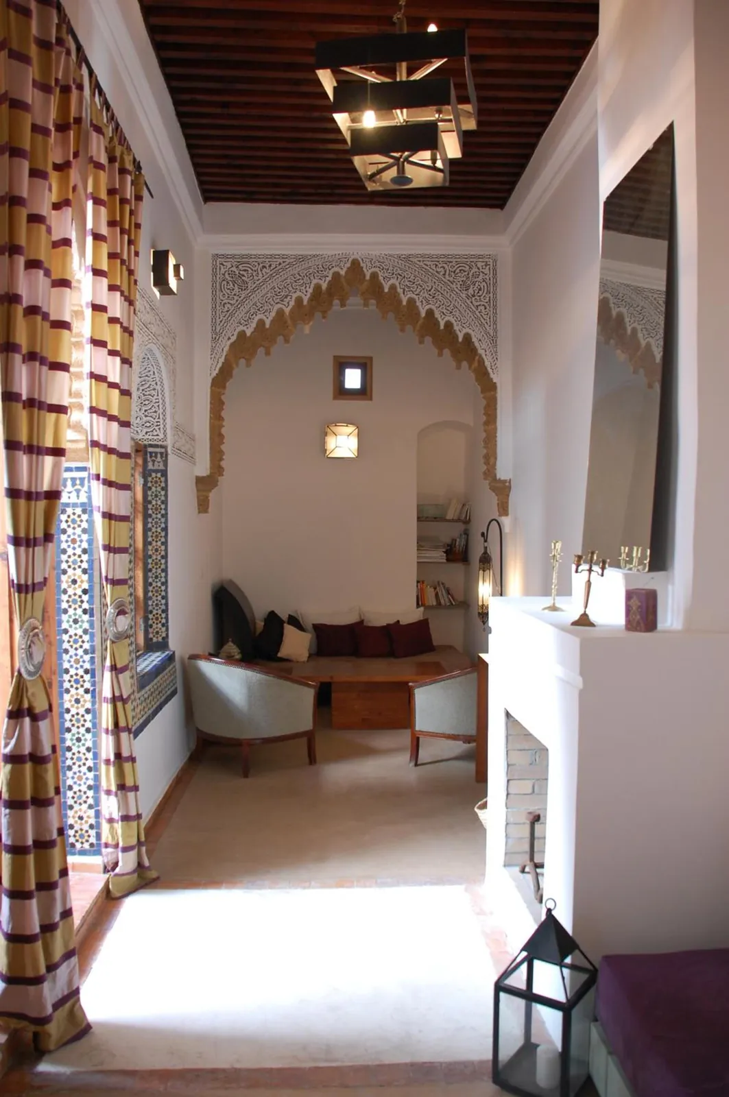 Un salon, ses rideaux rayés et sa cheminée