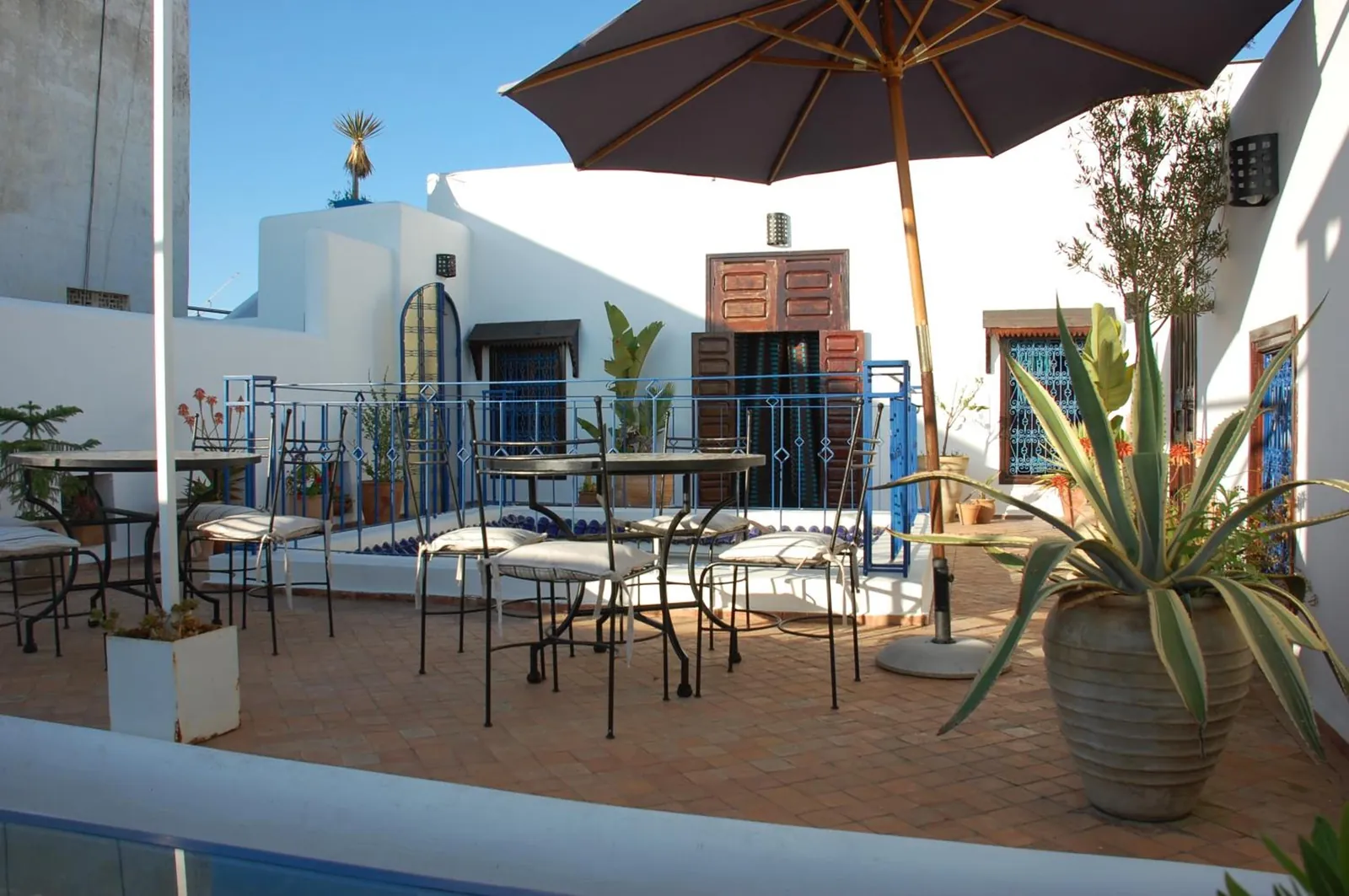 La terrasse, ses tables et le parasol